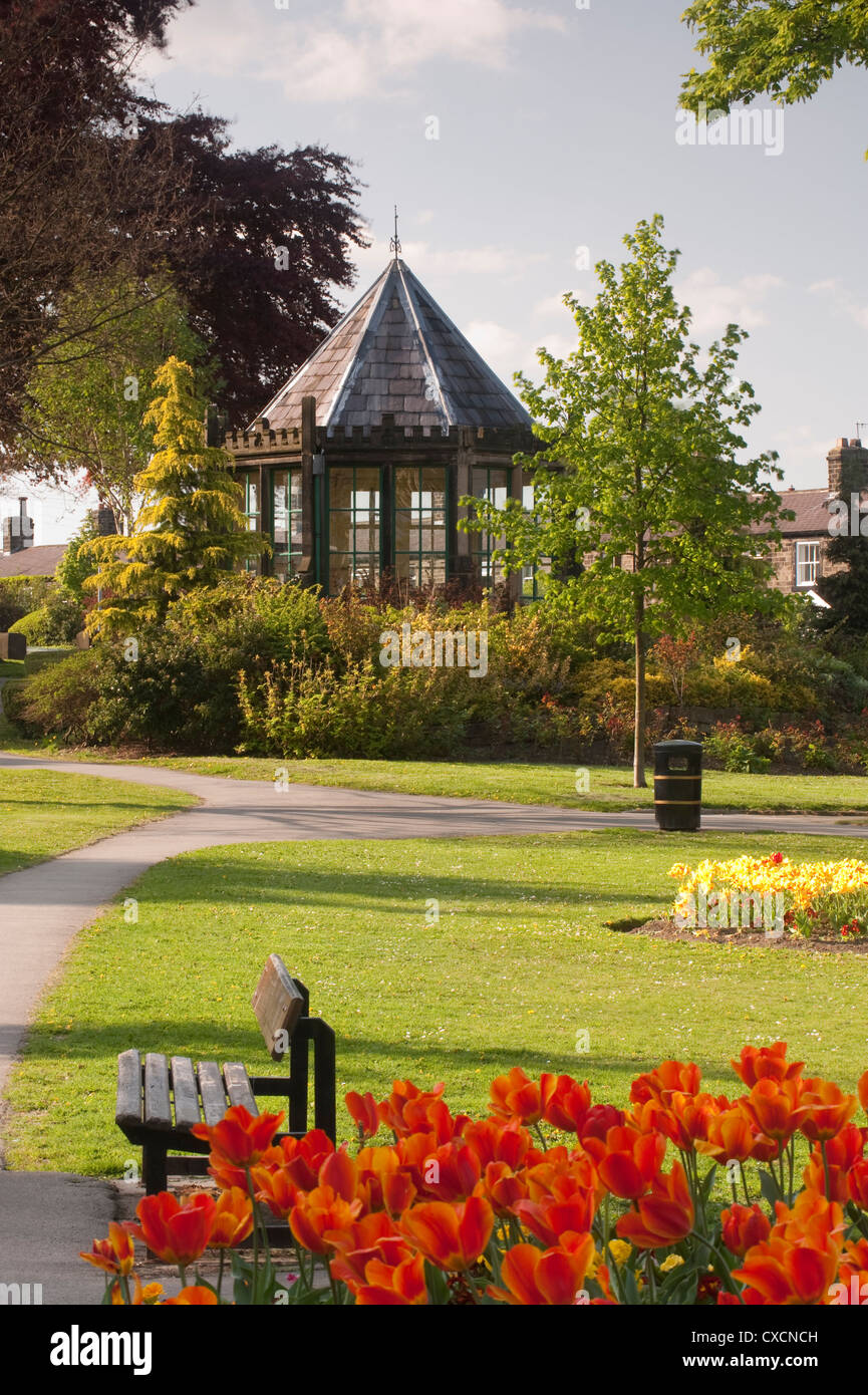 Schönen, angelegten Dorf park mit bunten Blumenbeeten, gepflegten Rasen & historische Gartenlaube (Round House) - Grange Park, Burley-in-Wharfedale, England. Stockfoto