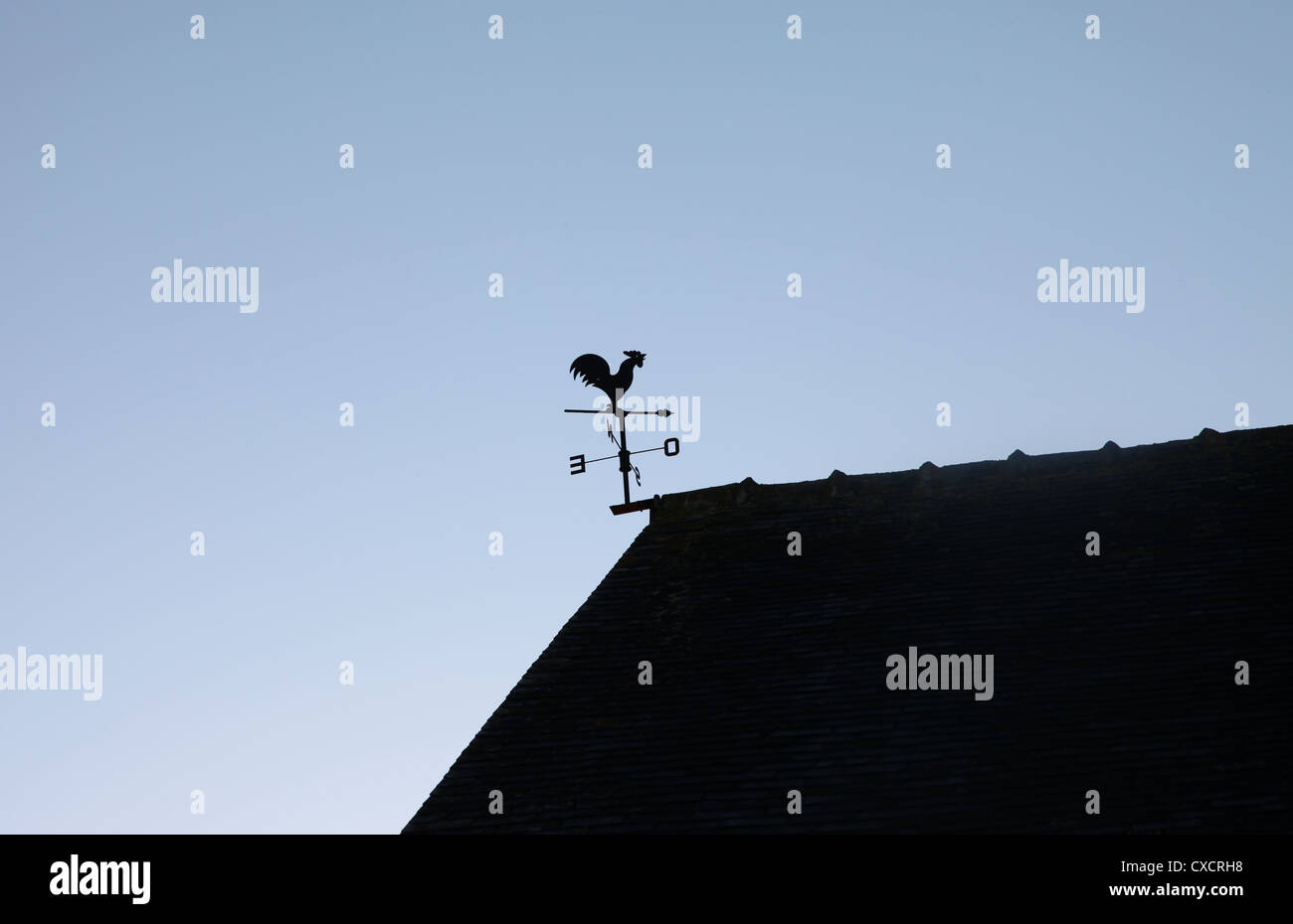 Es ist ein Foto von einem Wetterhahn auf einem Dach angebracht. Es gibt im Norden, Süden, Osten und Westen. Es ist wieder Licht Wetterhahn Stockfoto