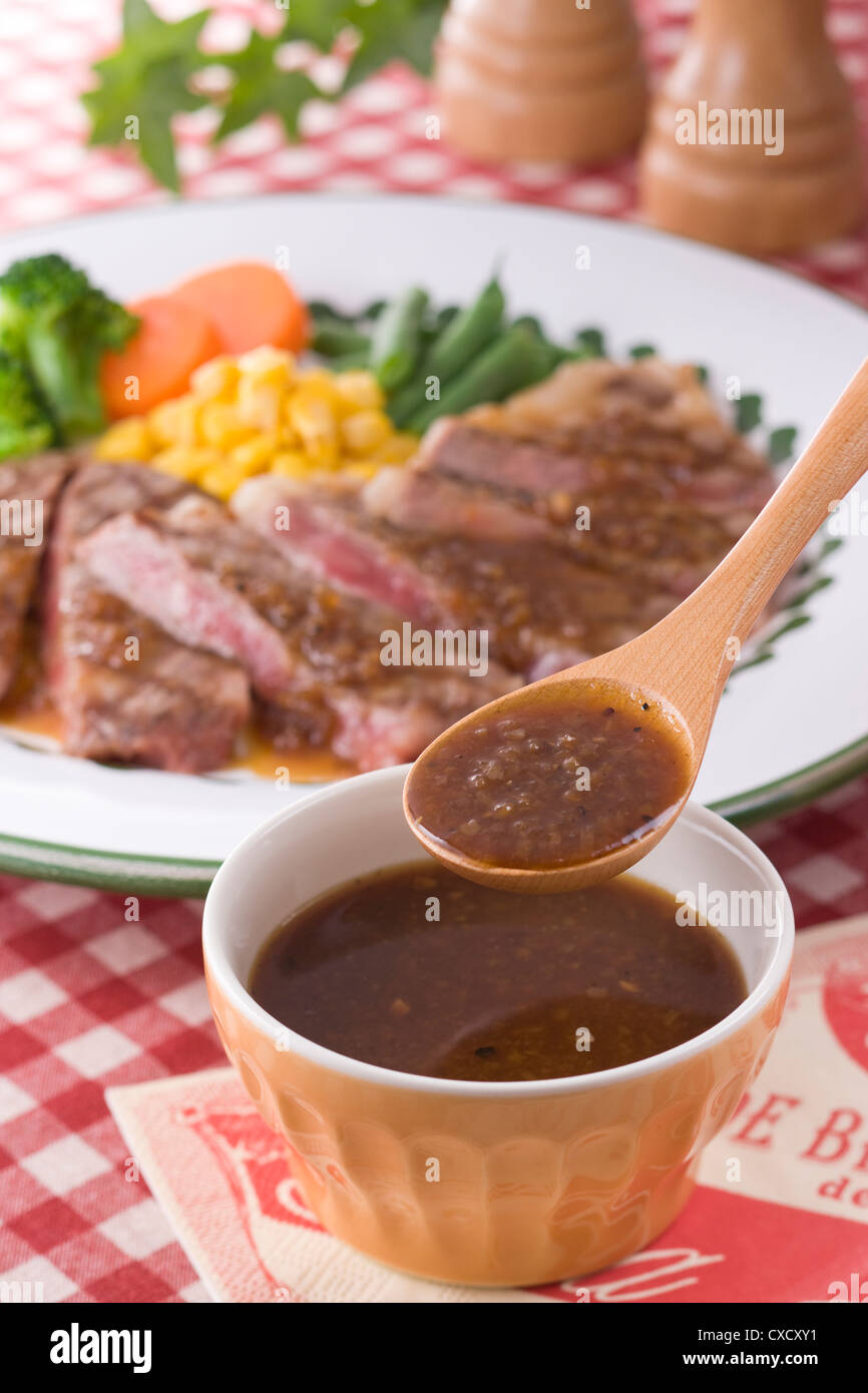 Scooping Steaksauce mit Löffel Stockfoto