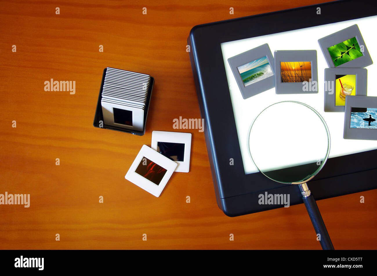 Draufsicht auf eine Lightbox mit Farbdias und eine Lupe Linse über ein Holztisch Stockfoto