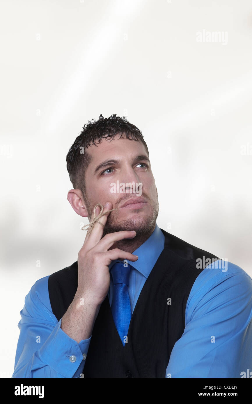 gut aussehend Geschäftsmann mit einem Stück Schnur gebunden, um seine Finger so Hes gonna nicht etwas vergessen Stockfoto