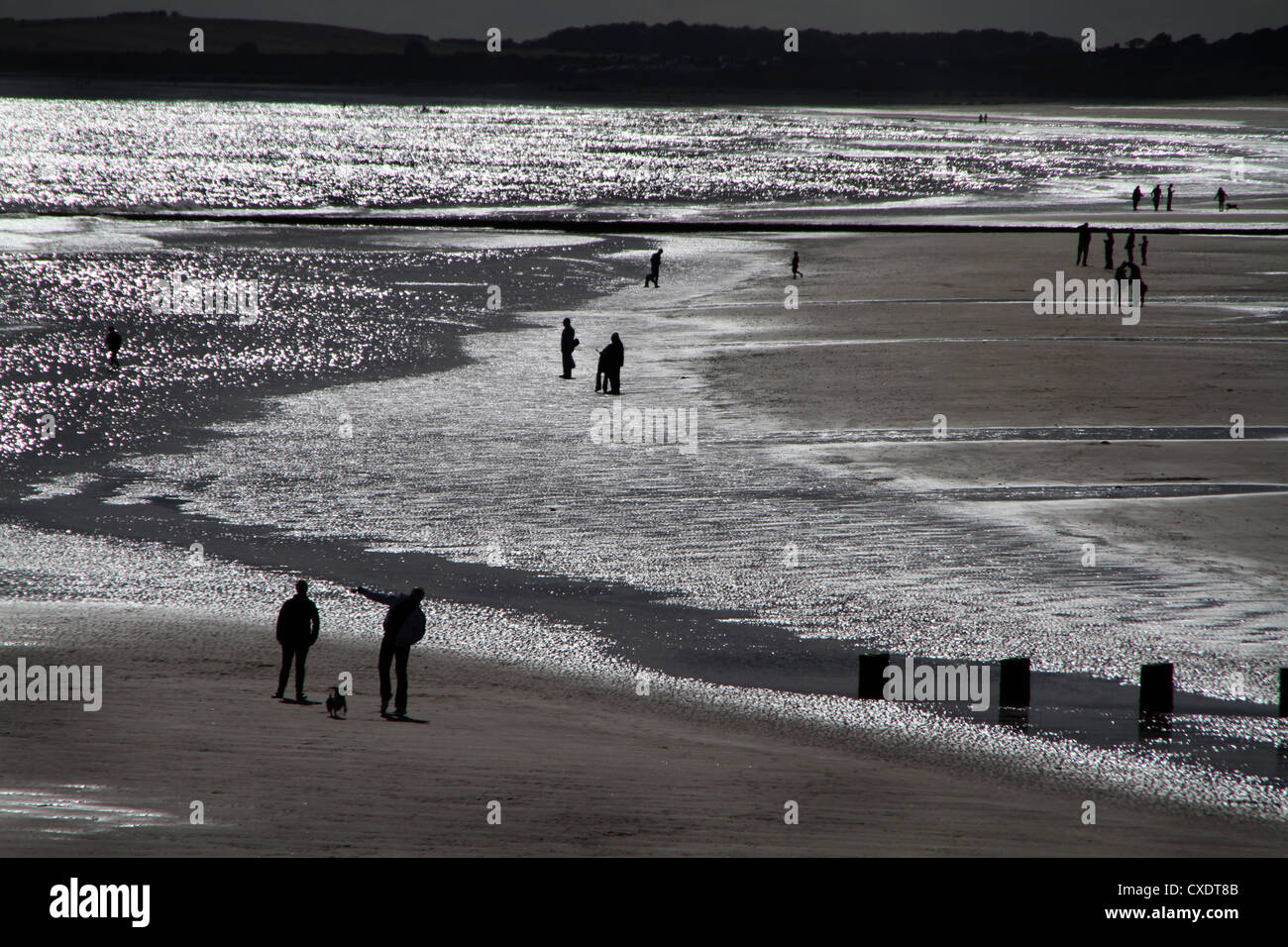 Silhouette des Menschen am sonnigen Strand bei Ebbe. Stockfoto