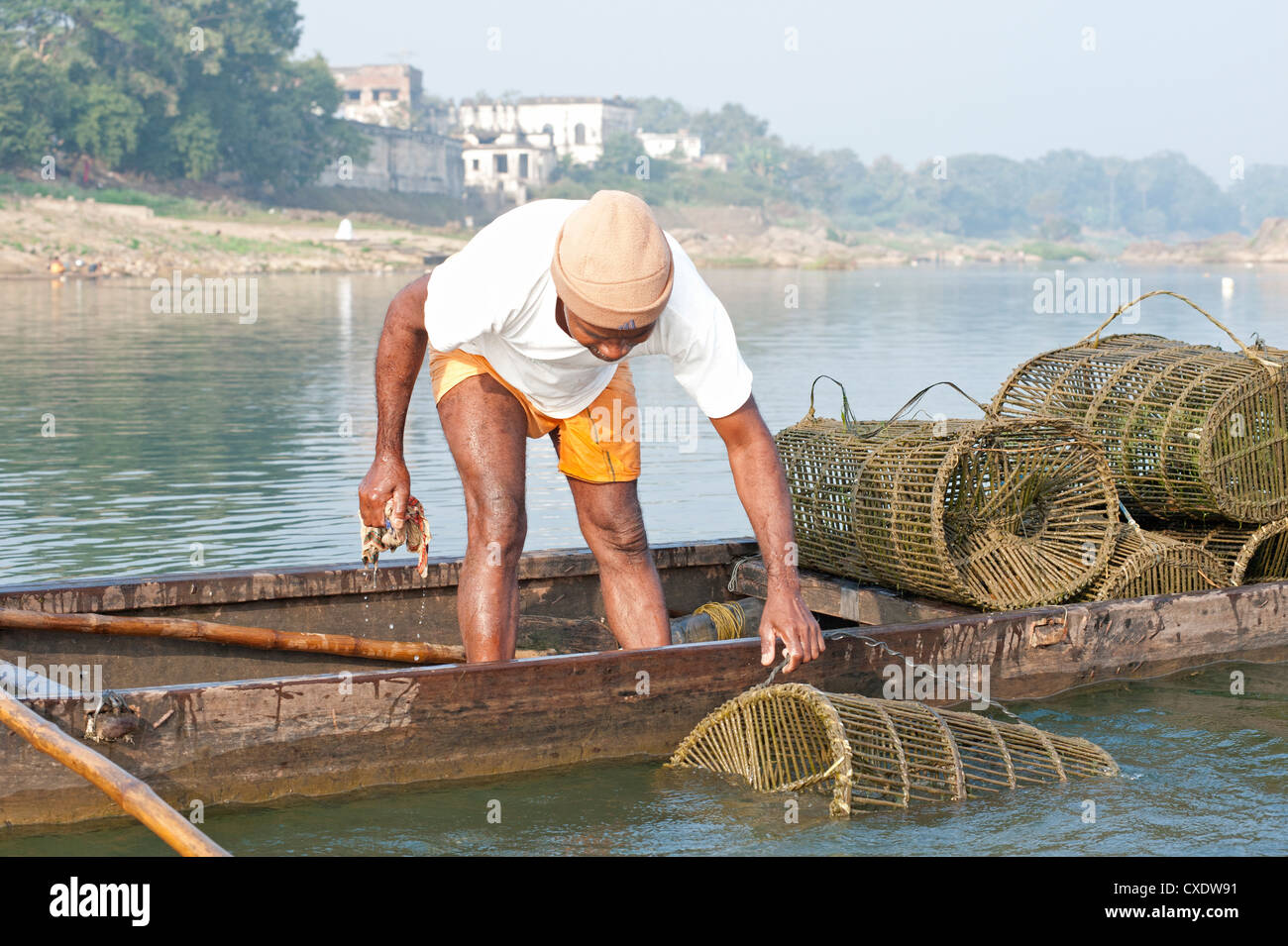 Fischer in Holzboot, Überprüfung seiner Fischerei Töpfe gemacht aus Kokos und Bambus, Fluß Mahanadi, Orissa, Indien, Asien Stockfoto