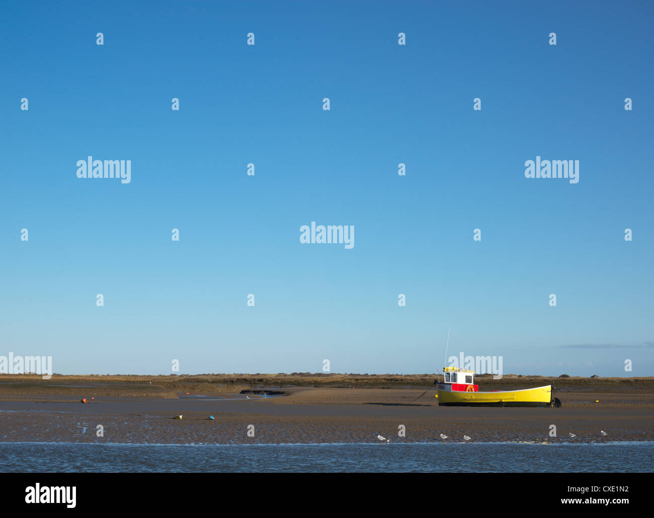 Ein einsamer Boot bei Ebbe am Brancaster Staithe, Norfolk, England Stockfoto