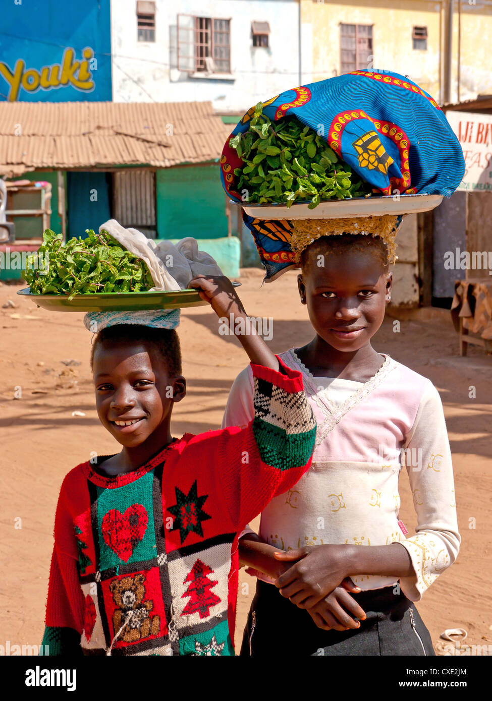 Zwei lokale Kinder Verkauf von Produkten ausgewogen zu produzieren, auf ihren Köpfen auf der Insel von Wurzeln, Gambia Stockfoto