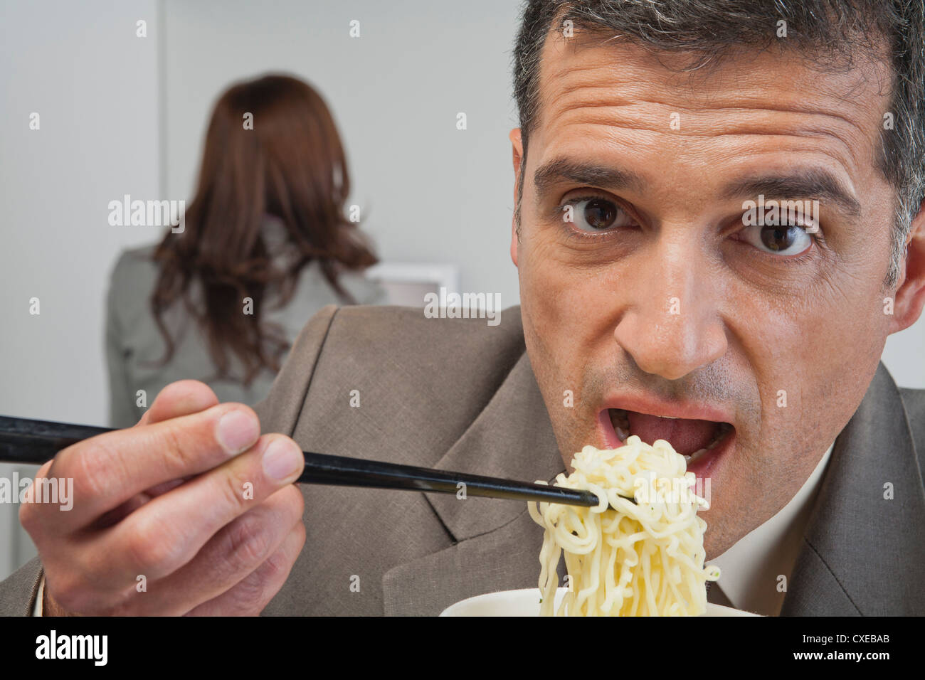 Reife Geschäftsmann Essen Ramen-Nudeln im Büro Stockfoto