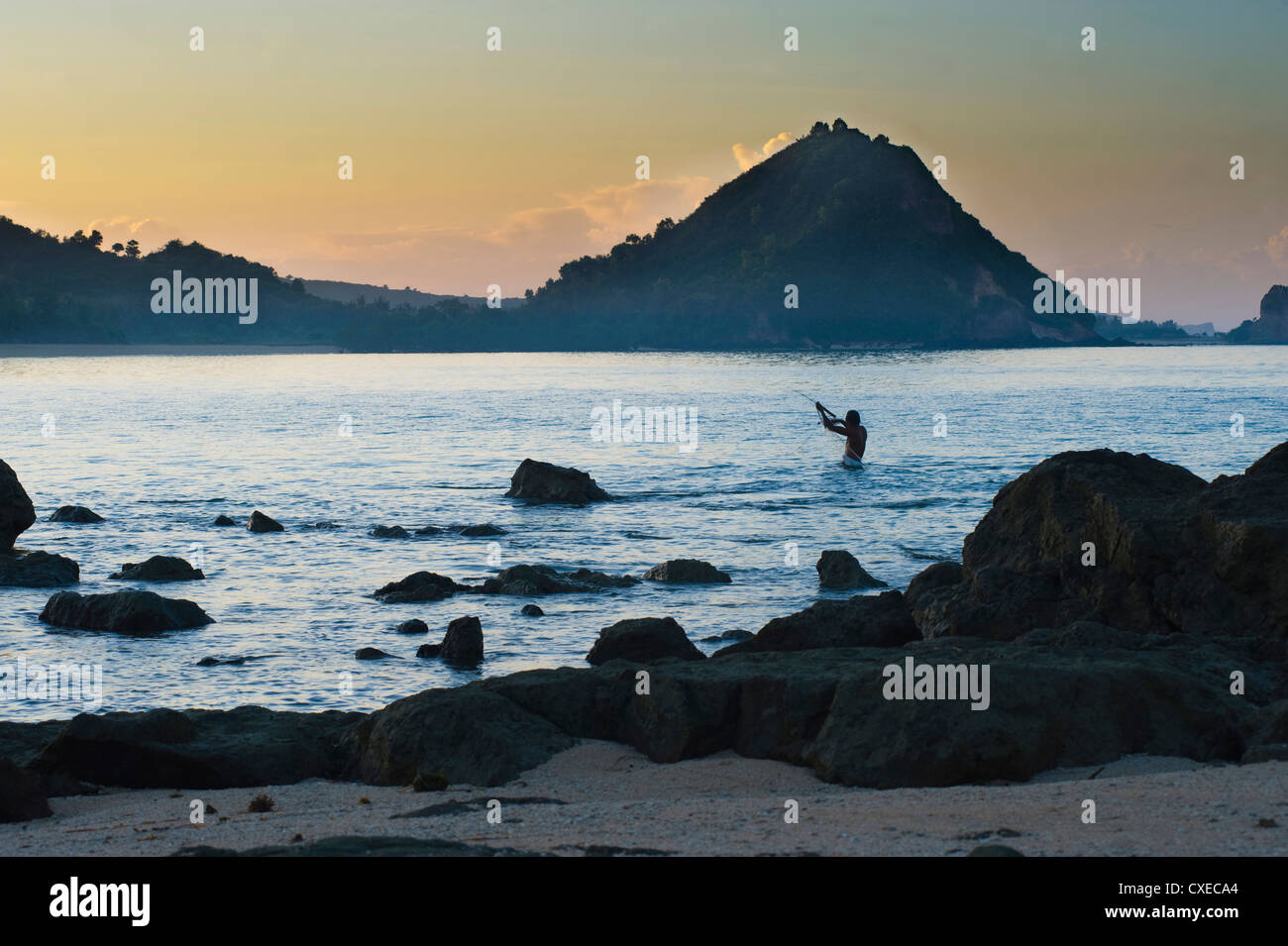 Mann Angeln mit einem Netz bei Sonnenaufgang am Strand von Kuta, Lombok, Indonesien, Südostasien, Asien Stockfoto