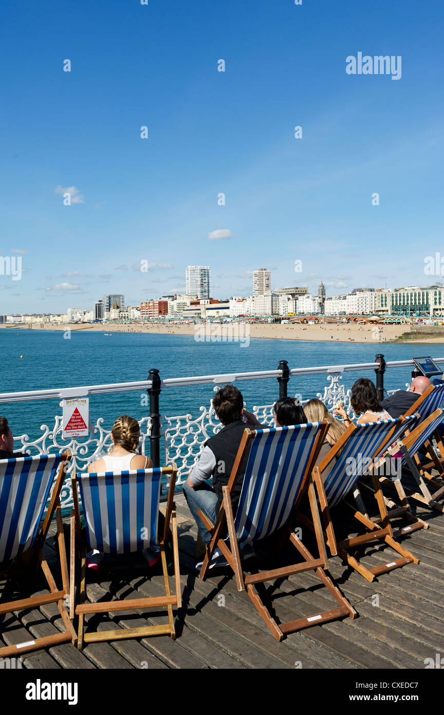 Leute sitzen in Liegestühlen am Pier von Brighton Stockfoto
