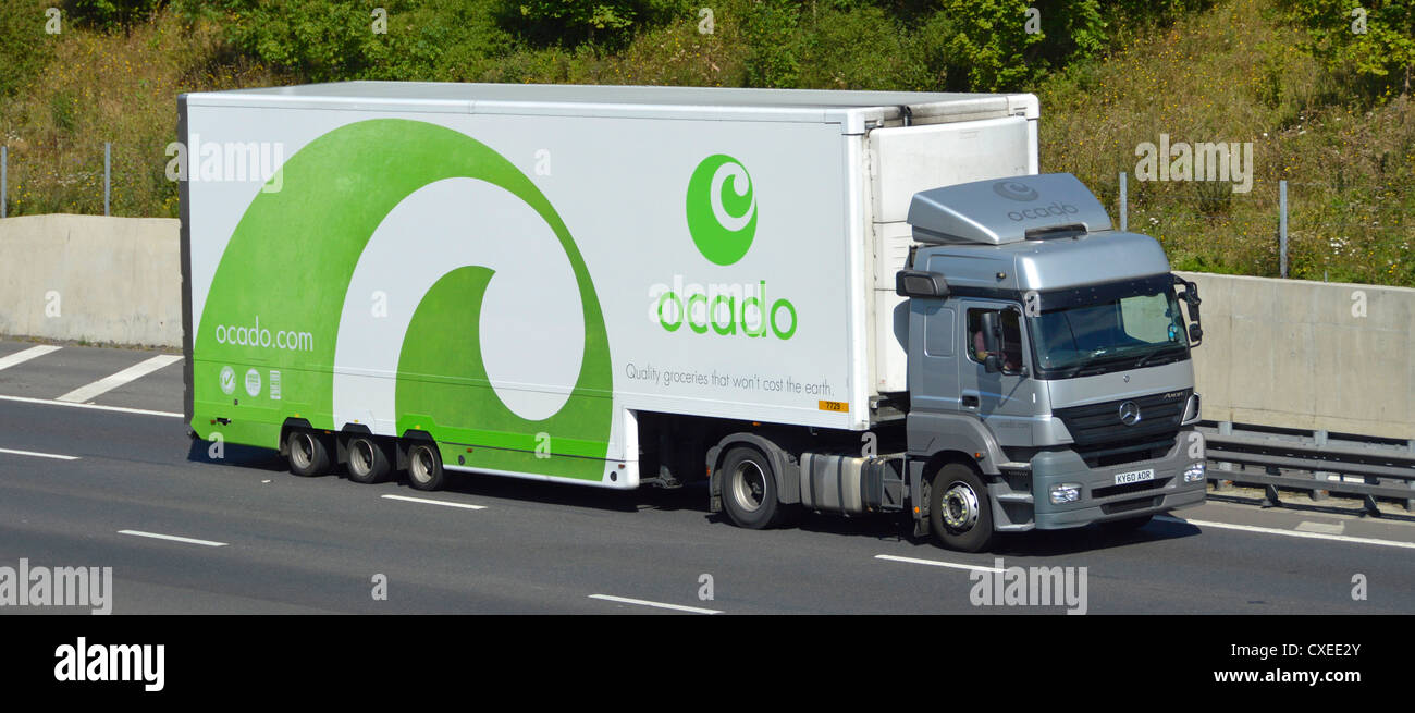 Ocado, Seitenansicht, weißer Lebensmittelanhänger mit grüner Grafik und seitlicher Vorderseite des mercedes Lieferwagens, der auf der englischen Autobahn M25 fährt Stockfoto