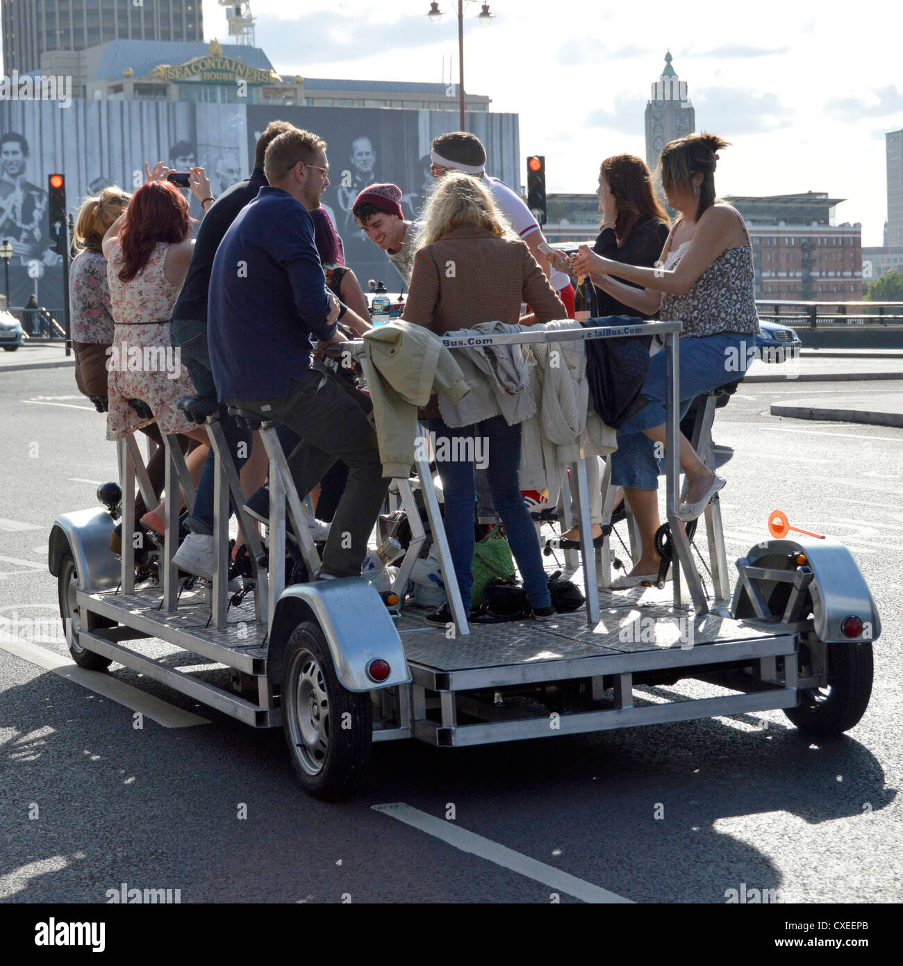 Eine Gruppe von Männern und Frauen genießen eine energiegeladene Tour durch London mit dem Pedi-Bus, auch bekannt als Party-Bike, Bier, Fahrradpedal, Crawler, Pedal, Pub, Party-Bike, England, Großbritannien Stockfoto