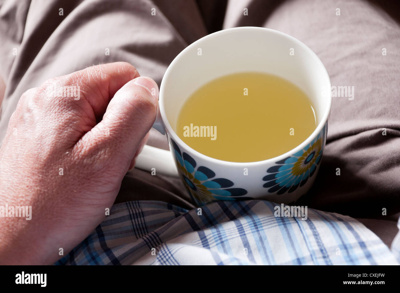 Menschen leiden mit kalten Holding Becher Lemsip in seinem Schoß. Stockfoto