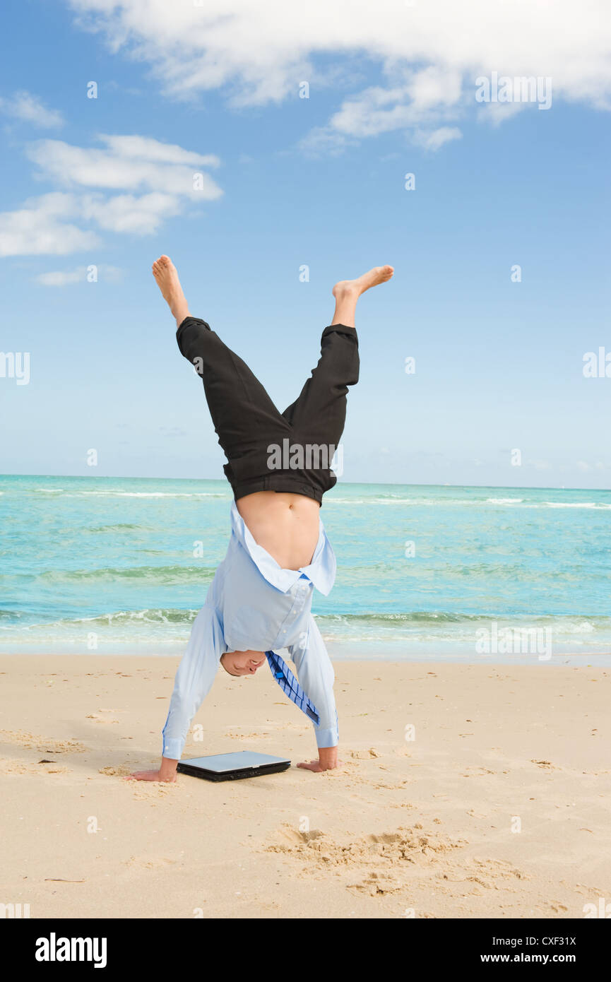 Geschäftsmann tun Handstand am Strand Stockfoto
