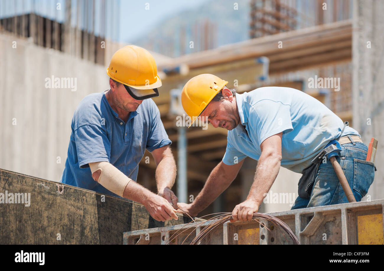 Authentische Bauarbeiter, die Zusammenarbeit bei der Installation von Zement Schalung frames Stockfoto