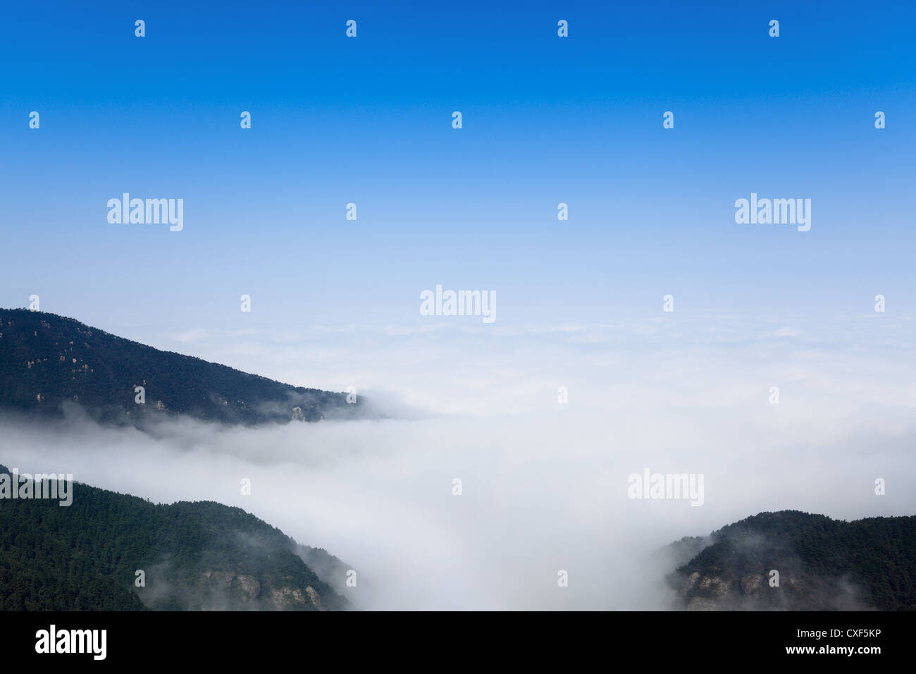 Wolken und Nebel schwebt unter Berggipfel Stockfoto