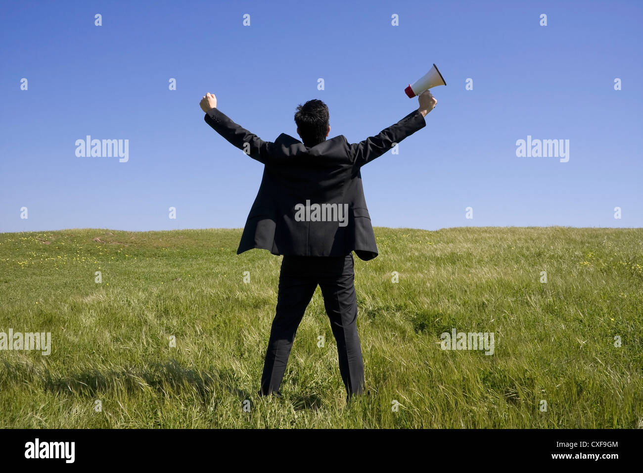 Männer halten ein Megaphon Geschäftsmann mit auf einem Feld mit einem blauen Himmel ausgestreckten Armen Stockfoto