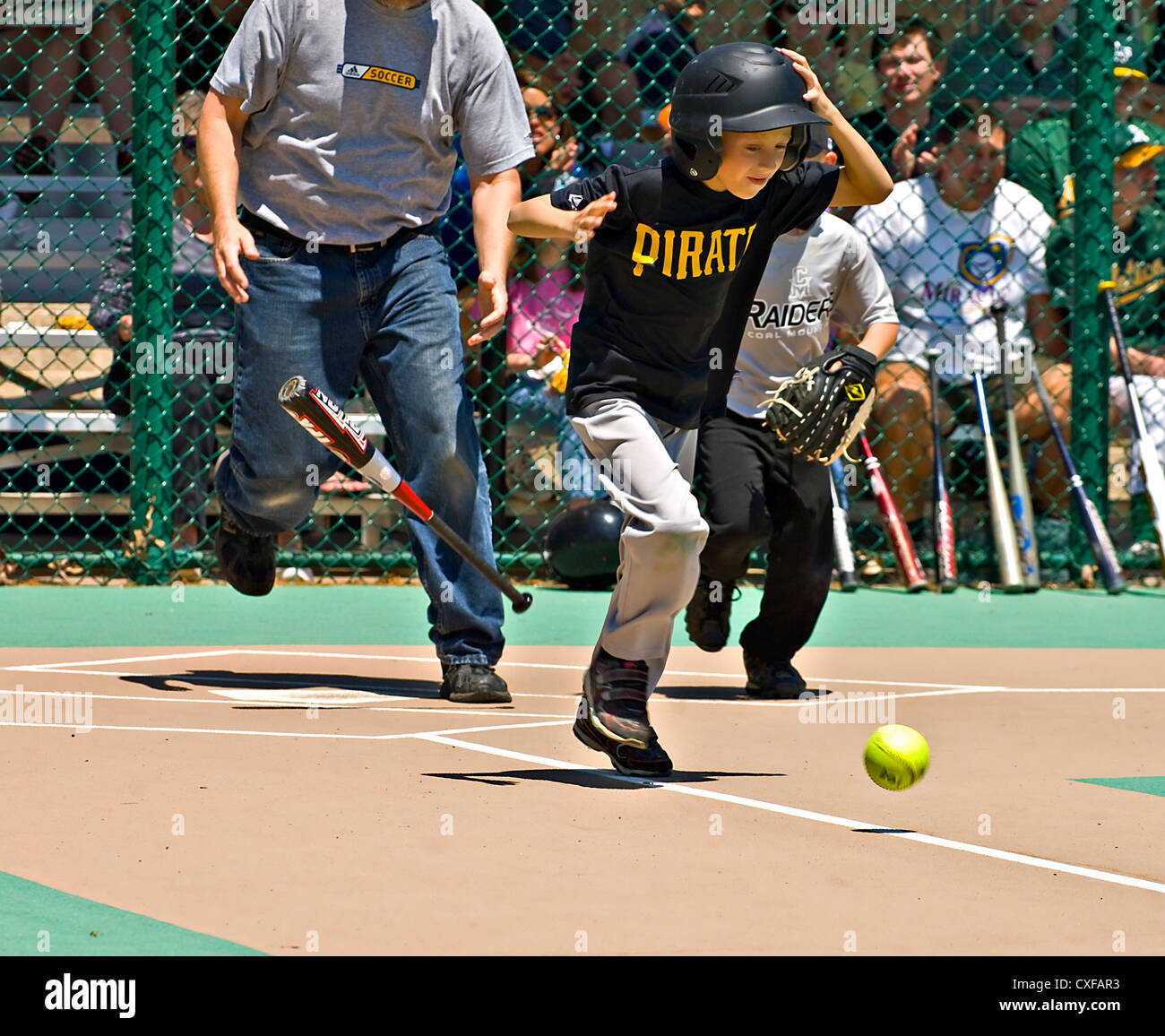 Ein kleiner Junge, fallen die Fledermaus zur ersten Base laufen nach, einen Hit in eine Wunder-Liga Softball-Spiel. Stockfoto