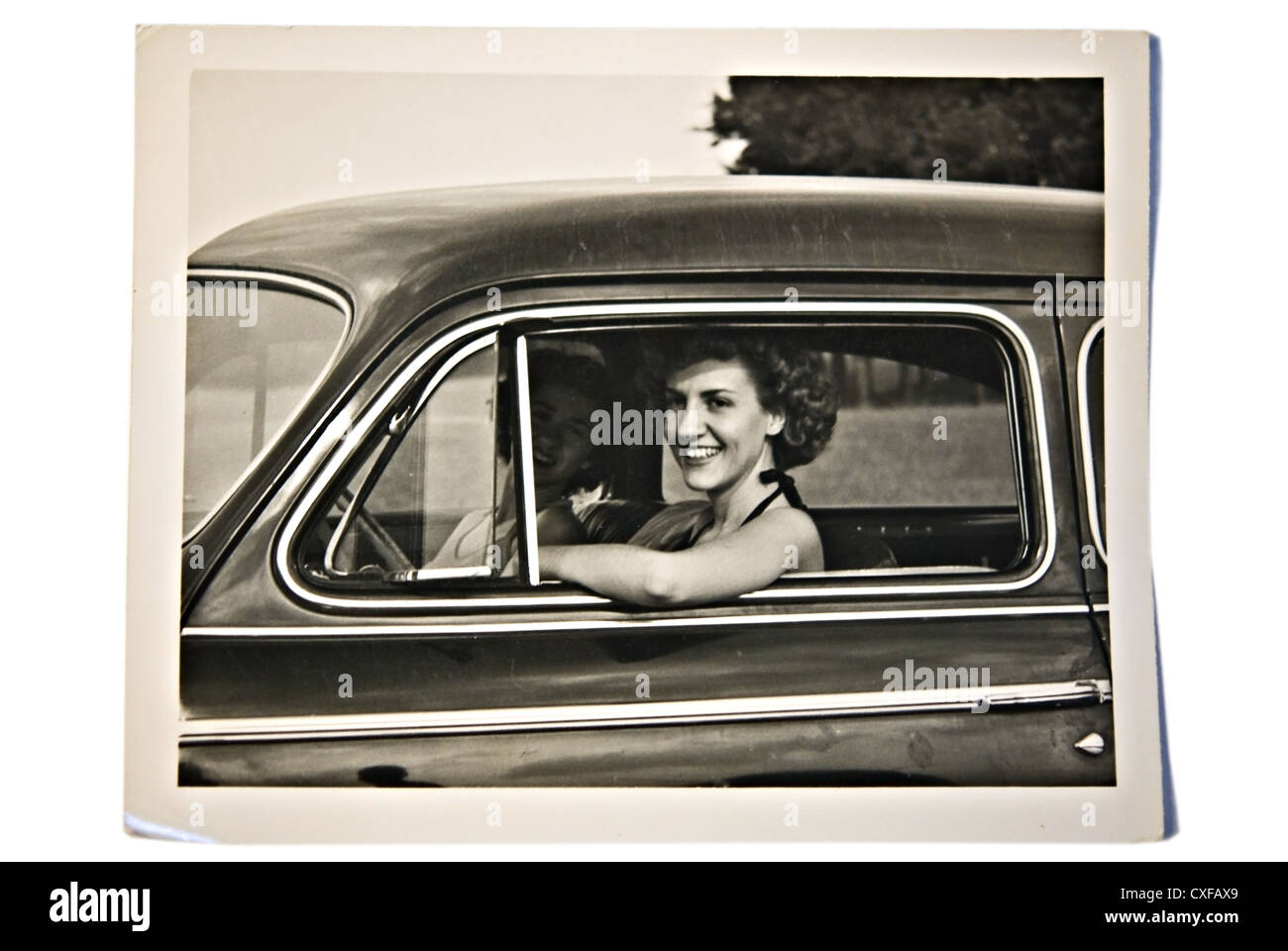 Zwei schöne junge Frauen in einem Auto, Jahrgang 1950. Die auf der Beifahrerseite ist in den Schatten und schwer zu erkennen. Stockfoto