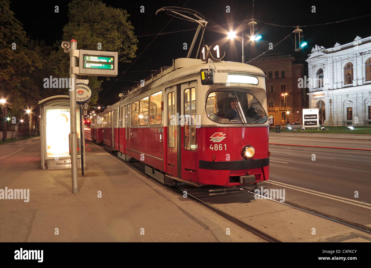 Eine Nr. 1 elektrische Straßenbahn warten an einer Straßenbahnhaltestelle in der Nacht in Wien, Österreich. Stockfoto