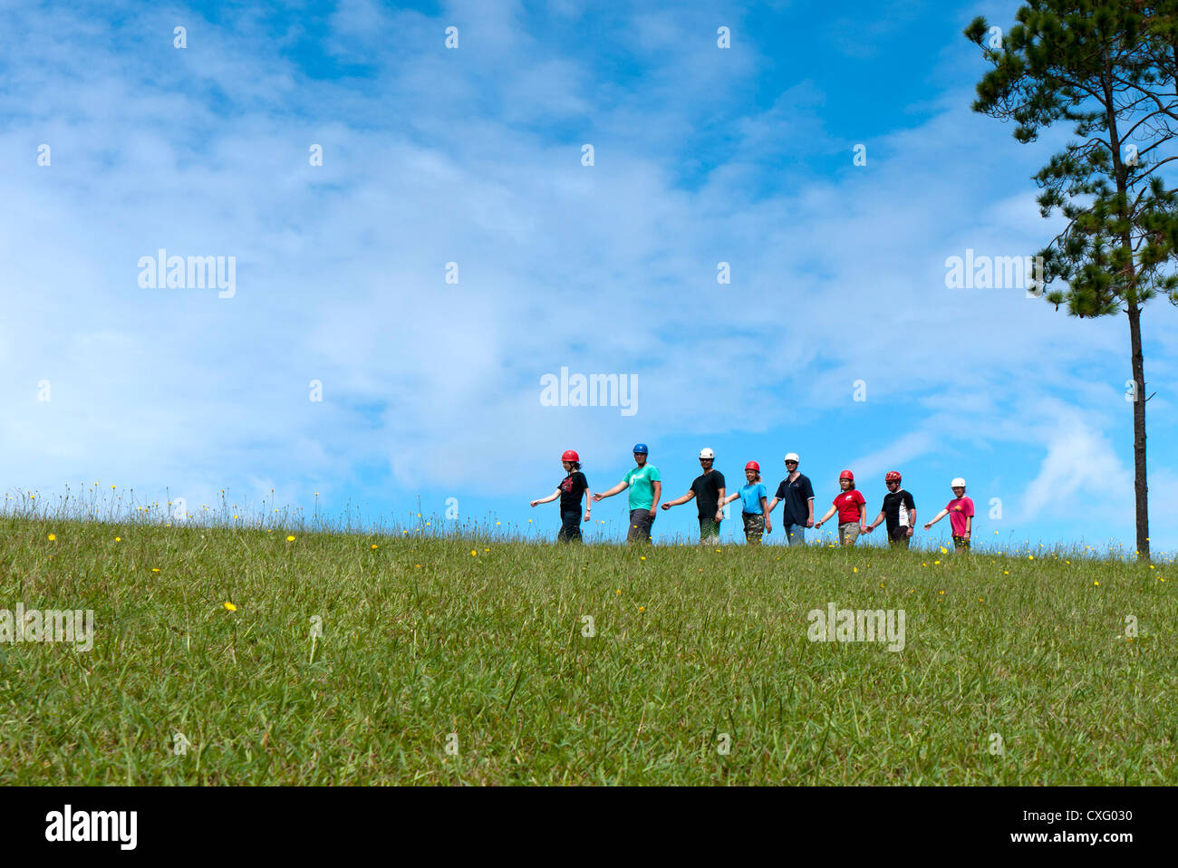 Eine Gruppe von Menschen zu Fuß auf einem Hügel an einem sonnigen Tag mit Schutzhelmen auf Stockfoto