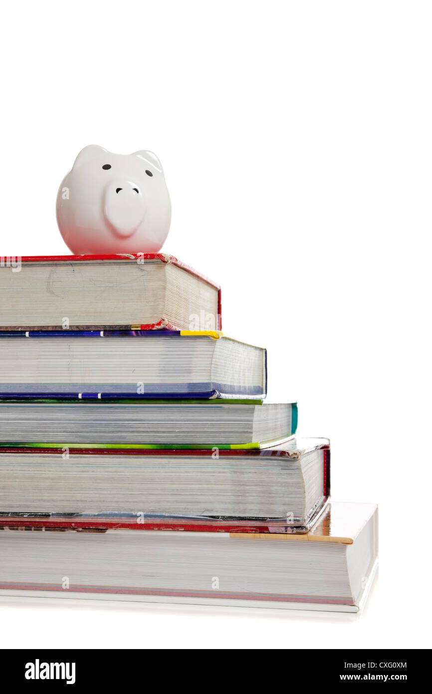 Stapel von Schulbüchern mit einem Sparschwein an der Spitze Stockfoto