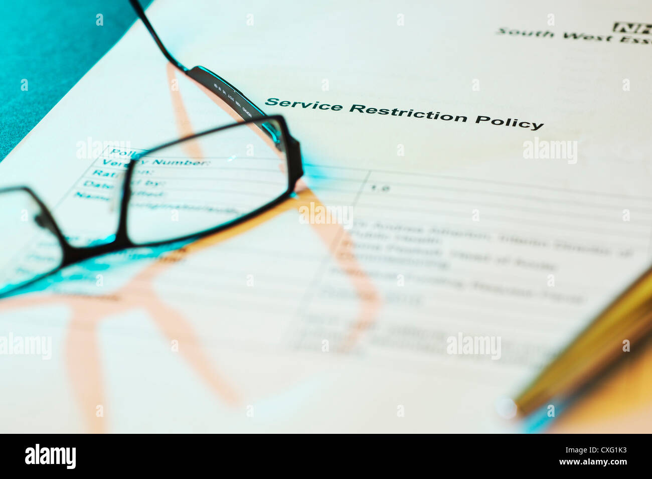 GP-Brille Handauflegen ein NHS Service Einschränkung Strategiepapier mit stimmungsvoller Beleuchtung und Stift Stockfoto