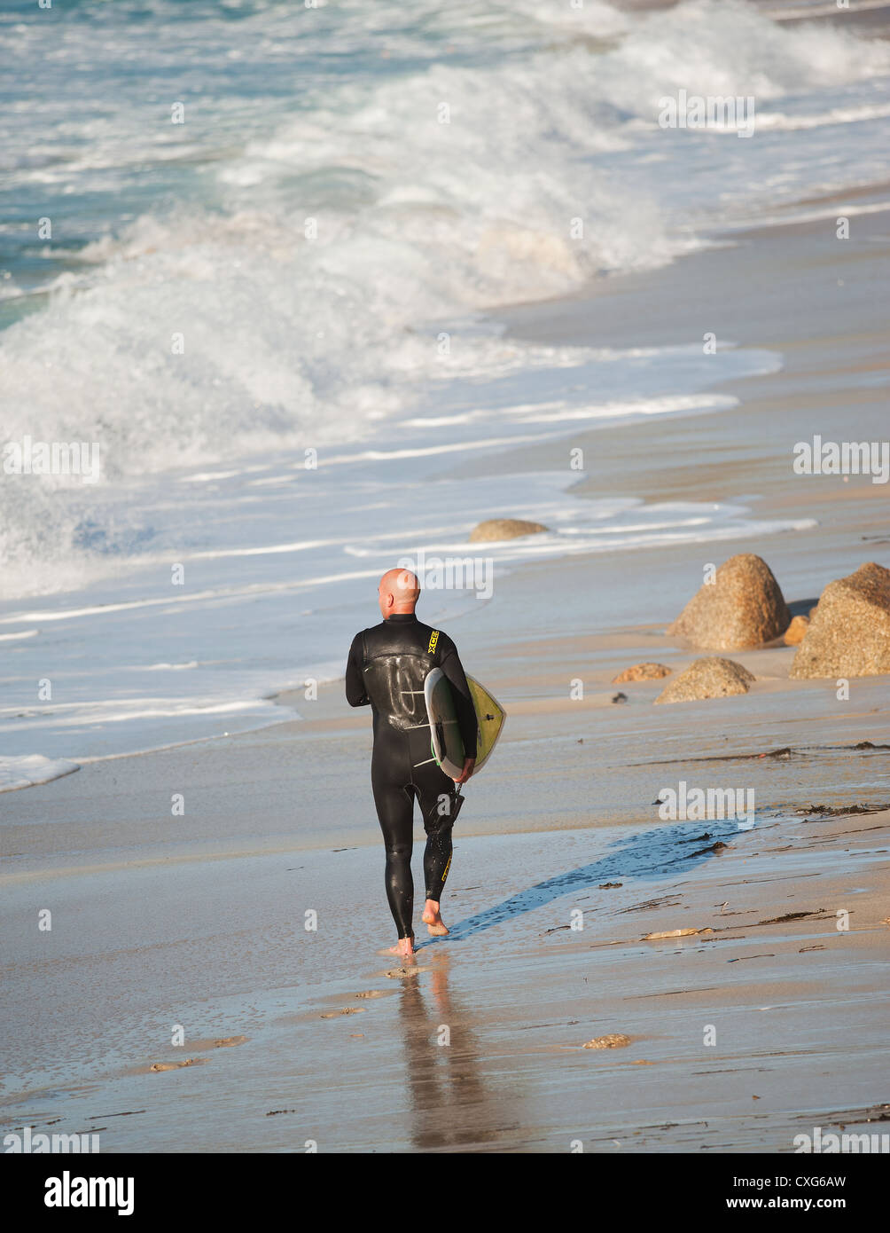 Ein Surfer, zu Fuß über den Strand von Sennen in Cornwall Stockfoto