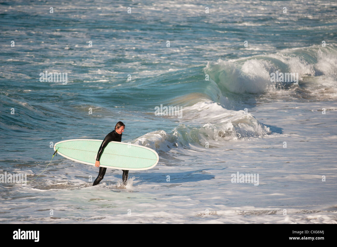 Ein Surfer zu Fuß aus dem Meer bei Sennen in Cornwall Stockfoto