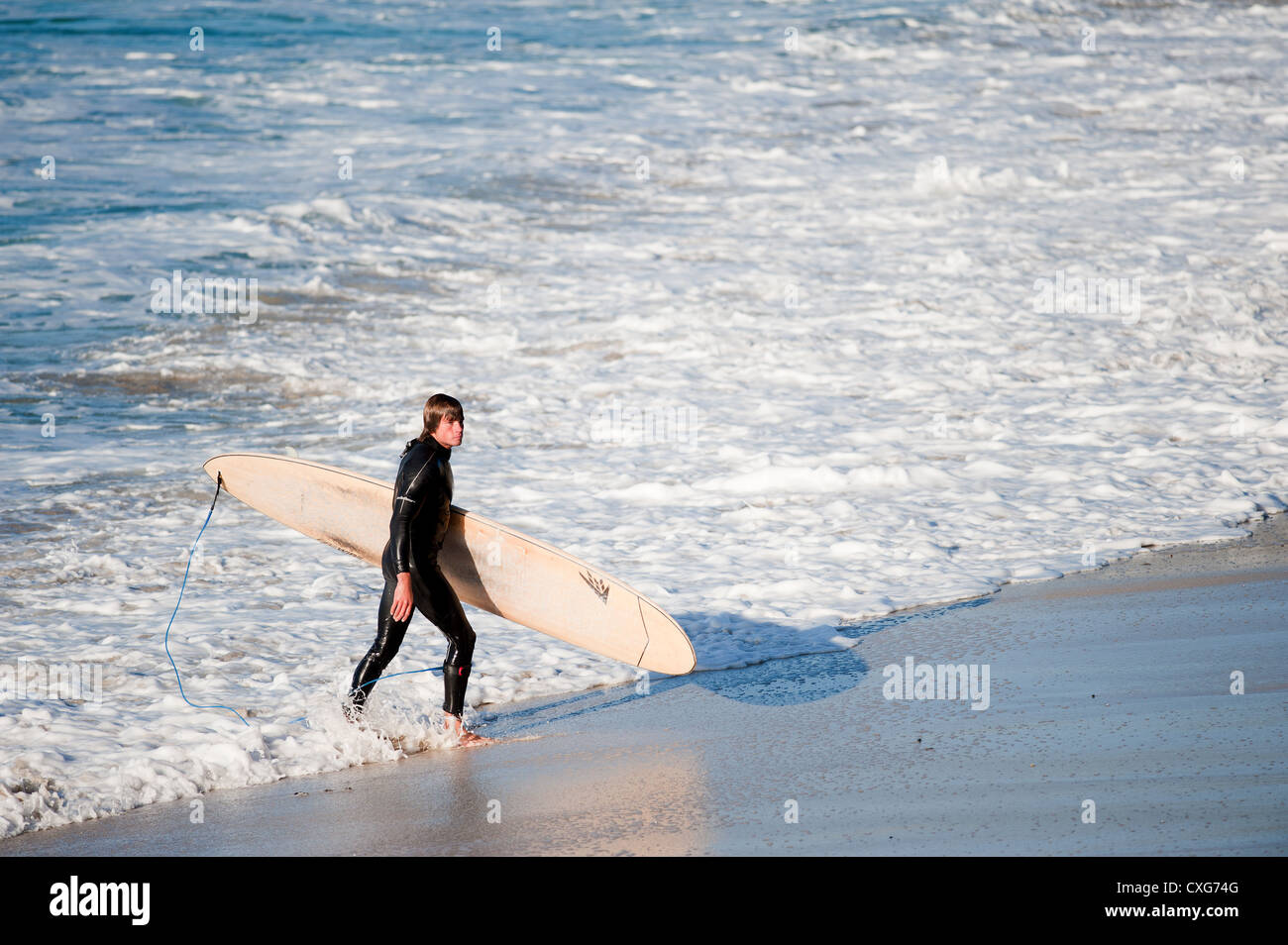 Ein Surfer zu Fuß aus dem Meer bei Sennen in Cornwall Stockfoto