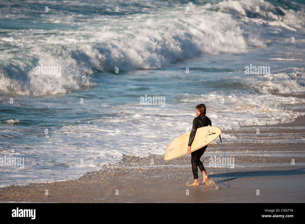 Ein Surfer zu Fuß ins Meer bei Sennen in Cornwall Stockfoto