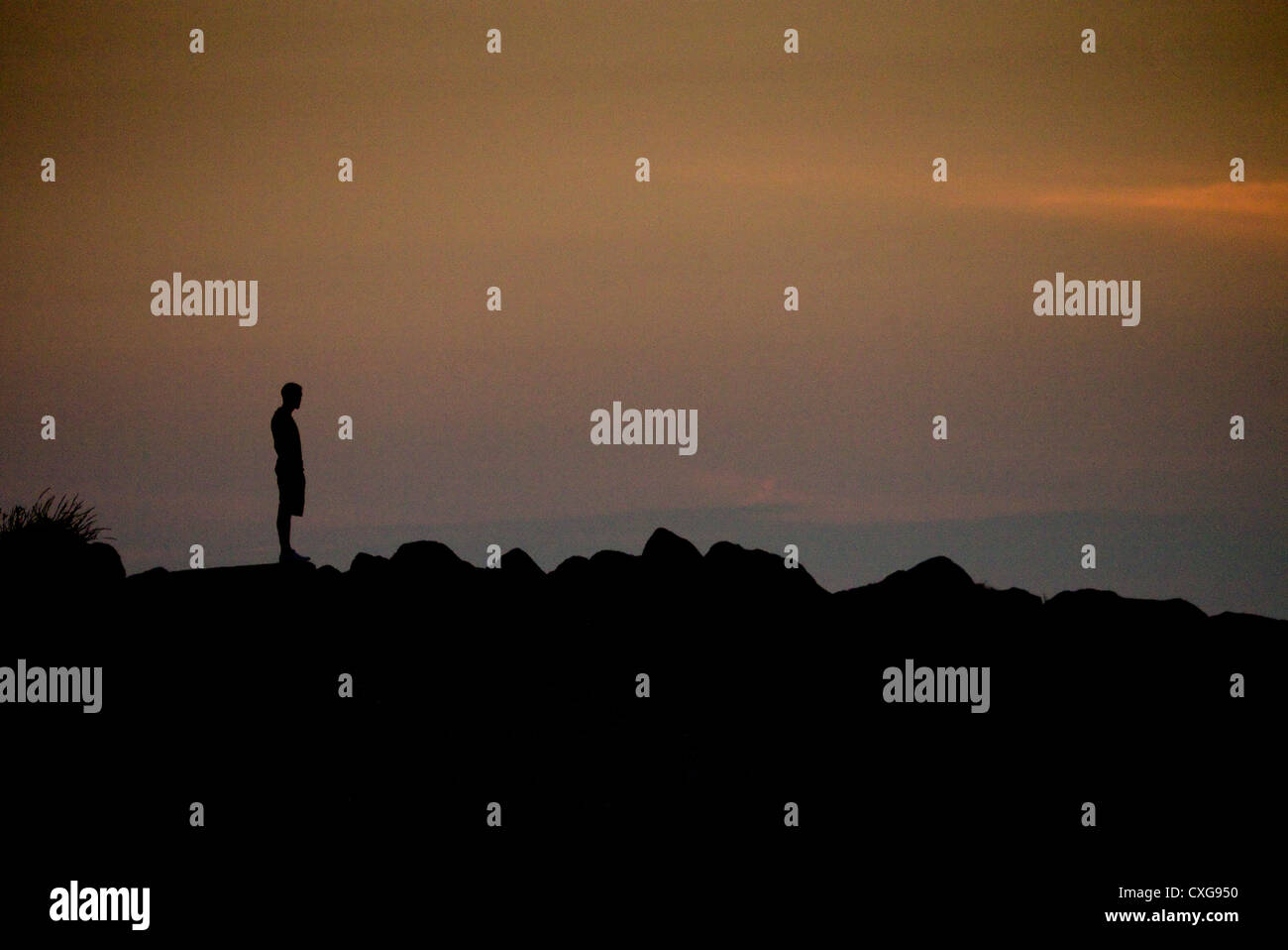 Mann, der bei Sonnenuntergang an einem Strand in Großbritannien Stockfoto