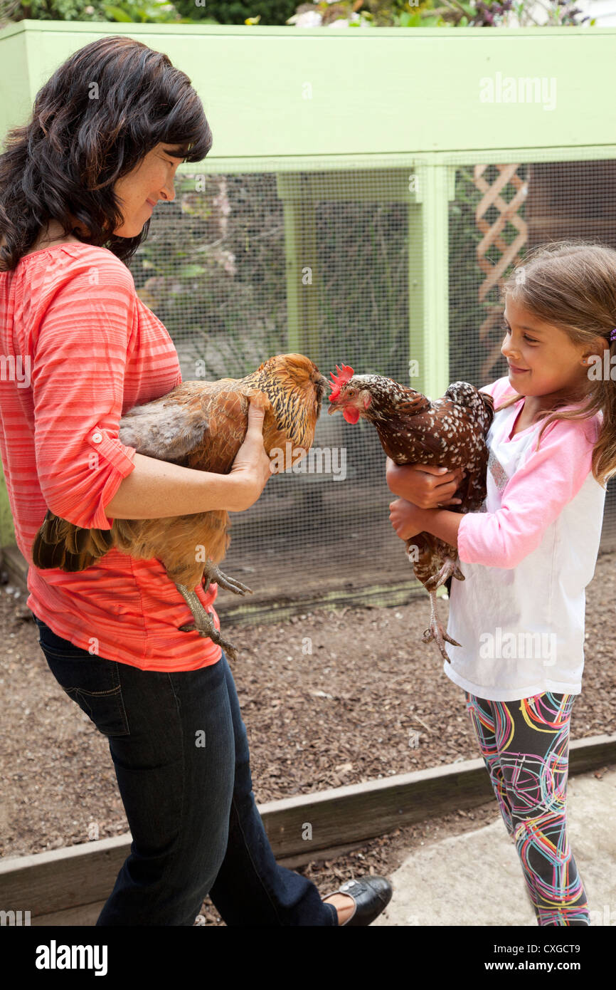 Eine Mutter und Tochter sind im Hinterhof halten ihre Hühner. Stockfoto