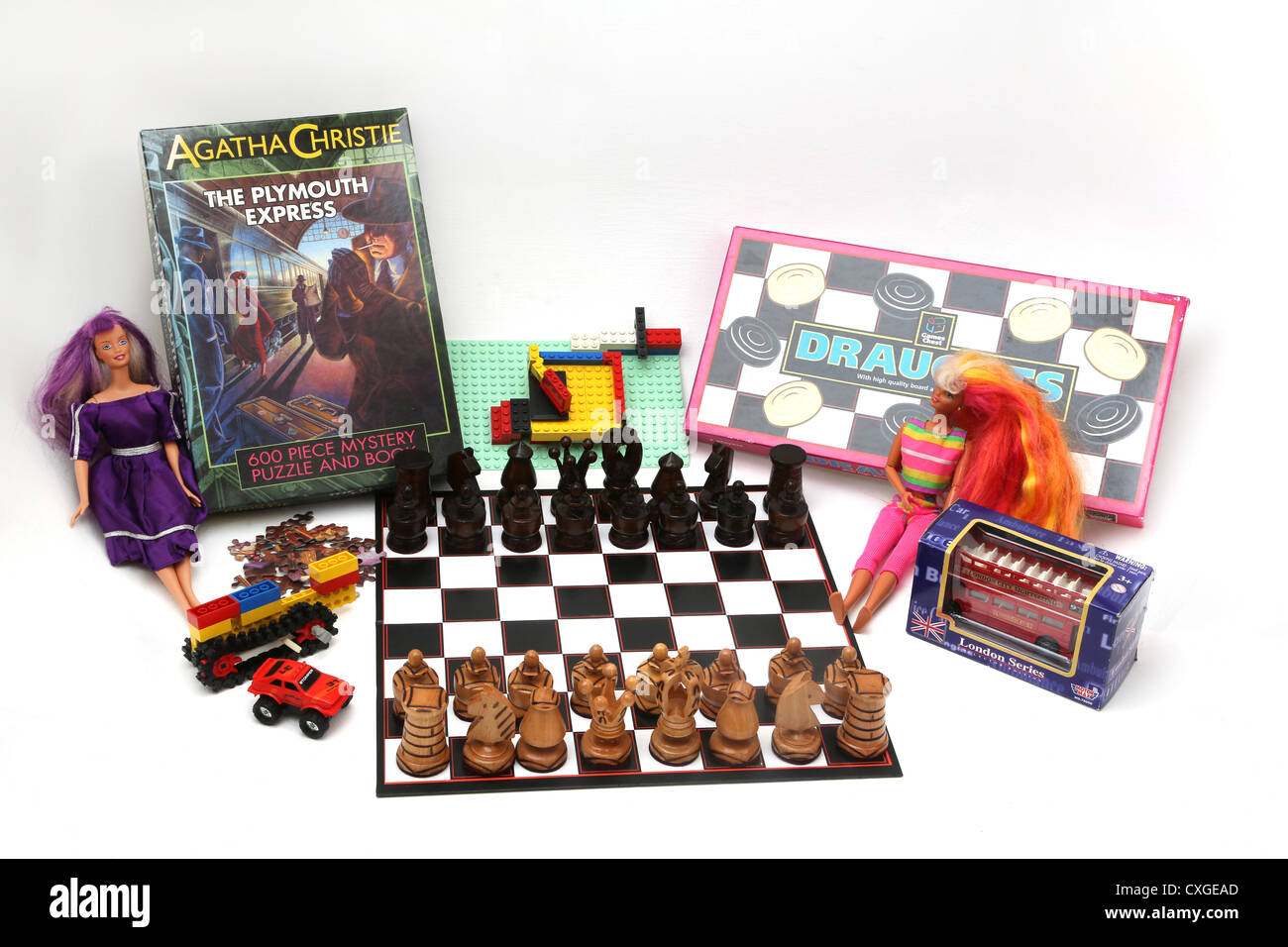 Eine Sammlung von spielen und Spielzeug - Zugluft, Barbies, Spielzeugautos, hölzerne Figuren, Lego und Puzzle Stockfoto