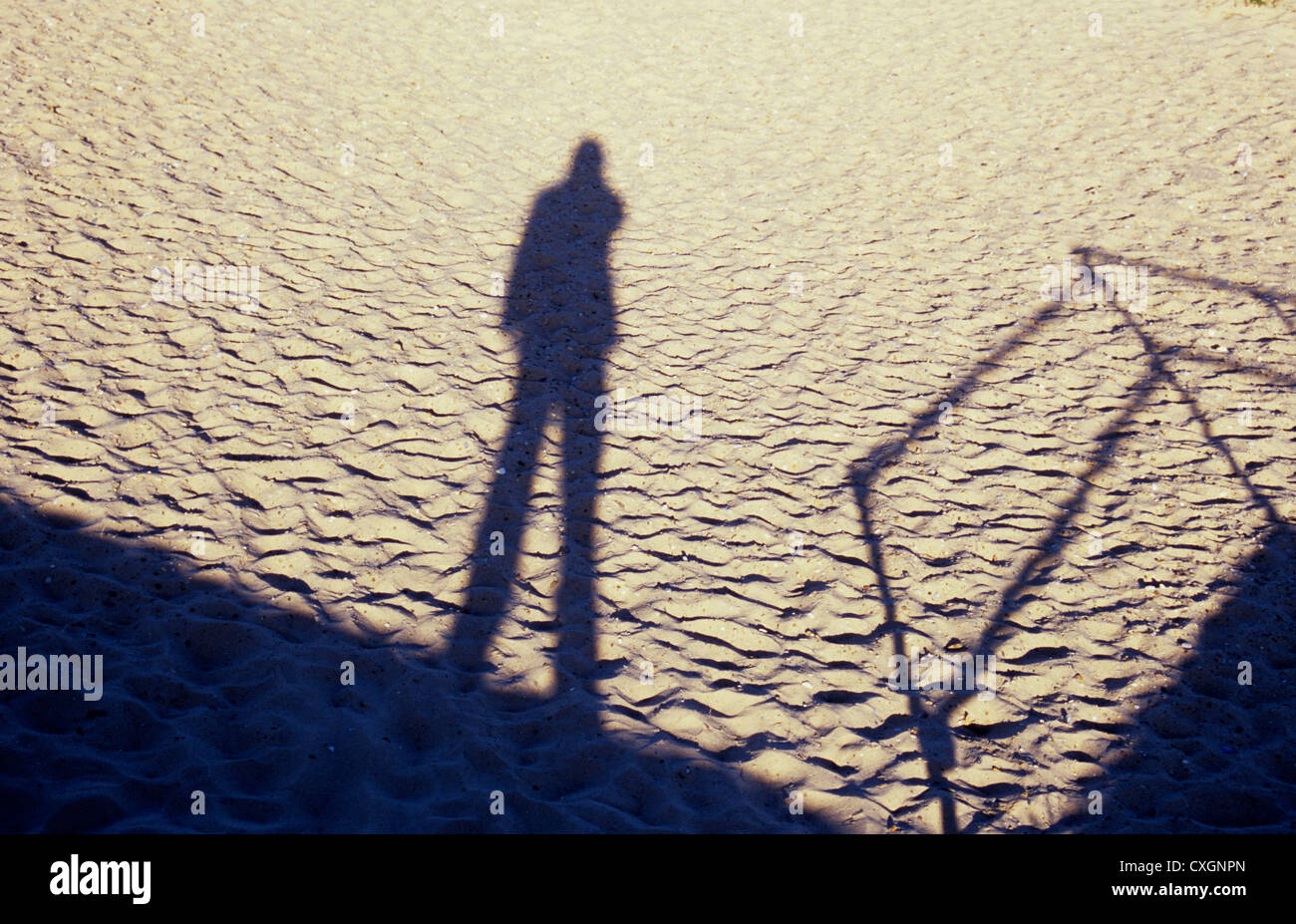 Schatten Sie auf sauber leicht trockenen Sand pockennarbige mit Fuß Vertiefungen der Figur stehen in der Nähe von Geländer Stockfoto