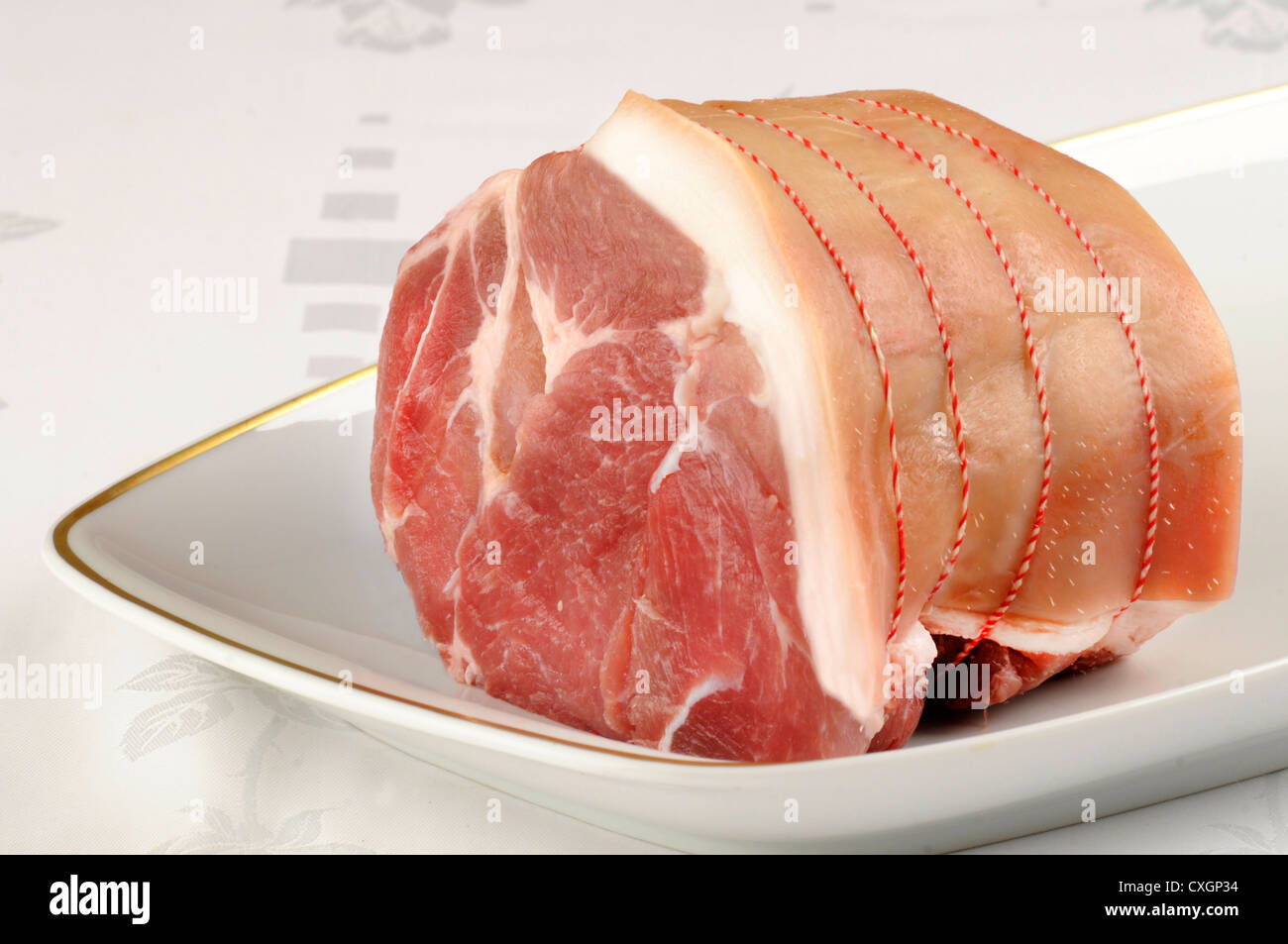 ein rohes Schweinefleisch Gelenk Fleisch auf weißem Teller und Tischdecke serviert Stockfoto