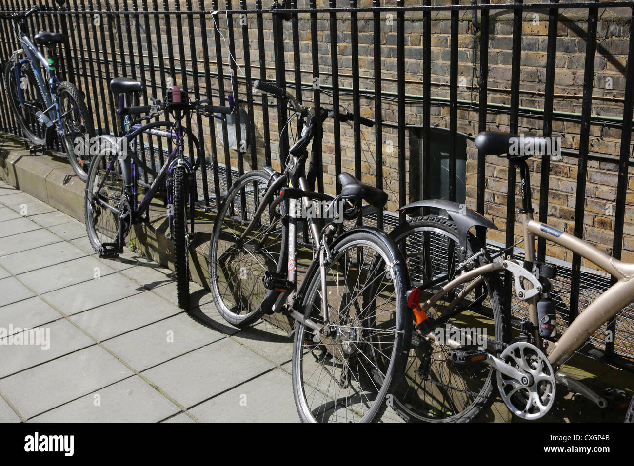 London England Fahrräder an Eisengeländern gesichert Stockfoto
