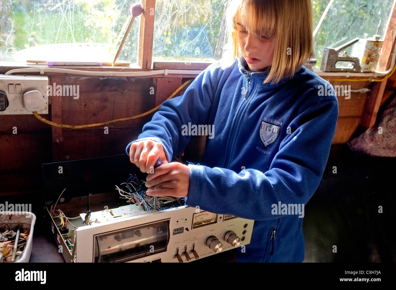 Ein 10 Jahres altes Mädchen nimmt auseinander einen alten Kassettenrecorder zu sehen wie es funktioniert Stockfoto