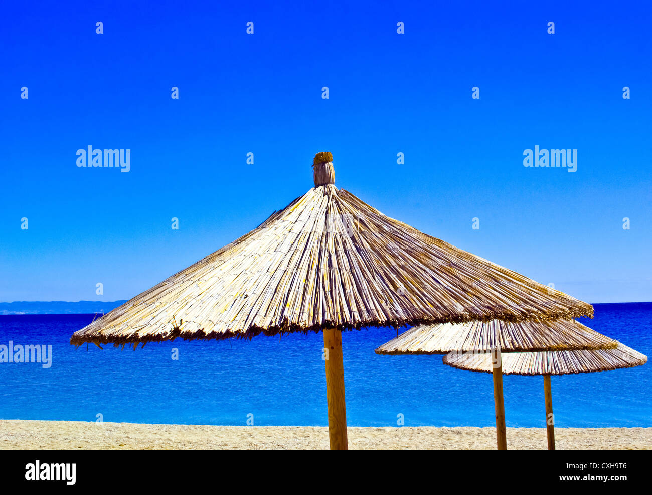 Ein Strohschirm an einem tropischen Strand mit blauem Himmel Stockfoto