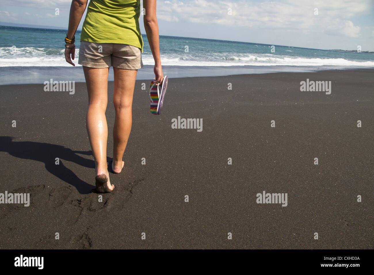 Indonesien. Junge Frau zu Fuß auf schwarzem sand Stockfoto