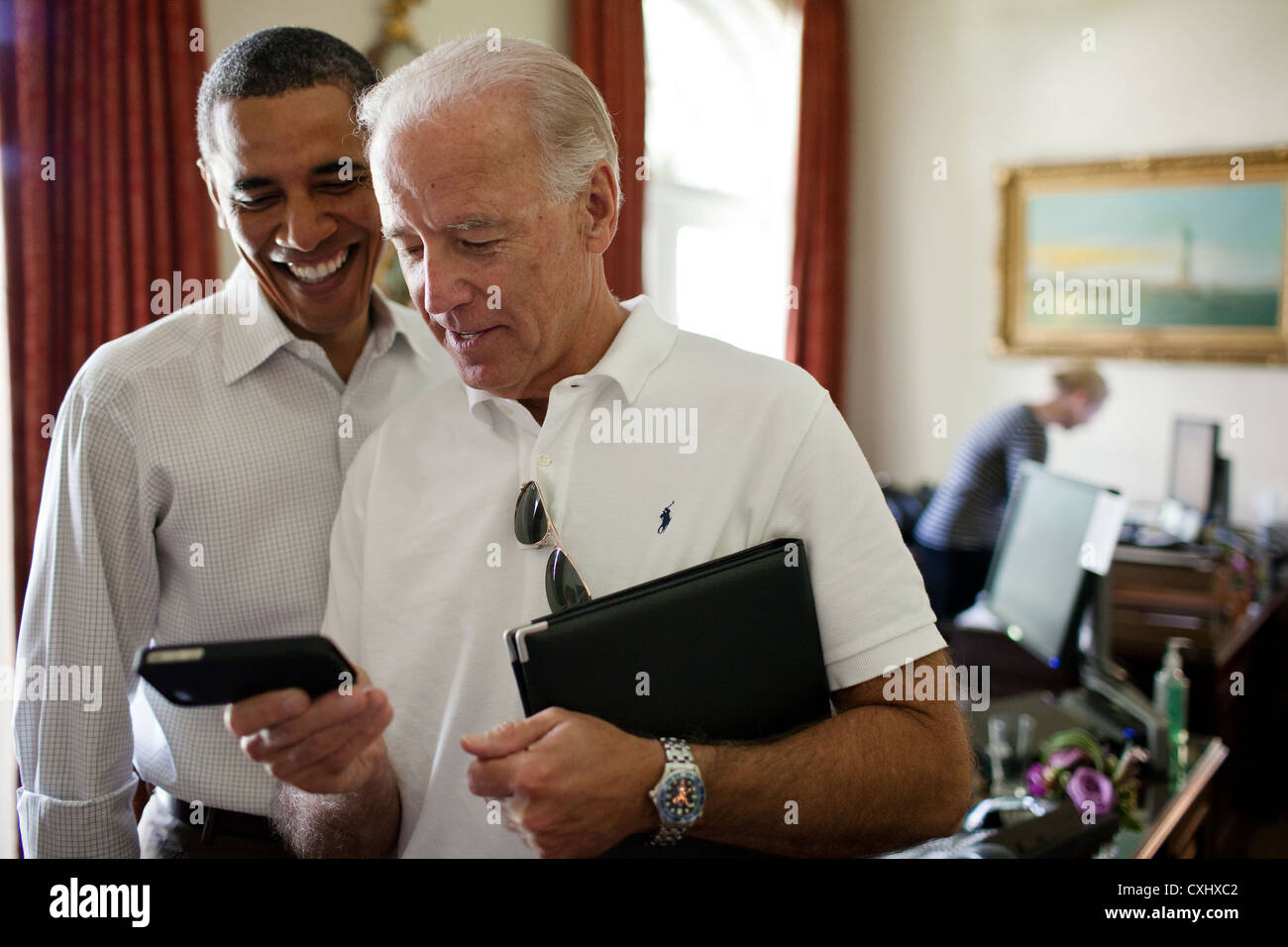 Vize-Präsident Joe Biden und Präsident Barack Obama Blick auf eine app auf einem iPhone 16. Juli 2011 in der äußeren Oval Office des weißen Hauses. Stockfoto