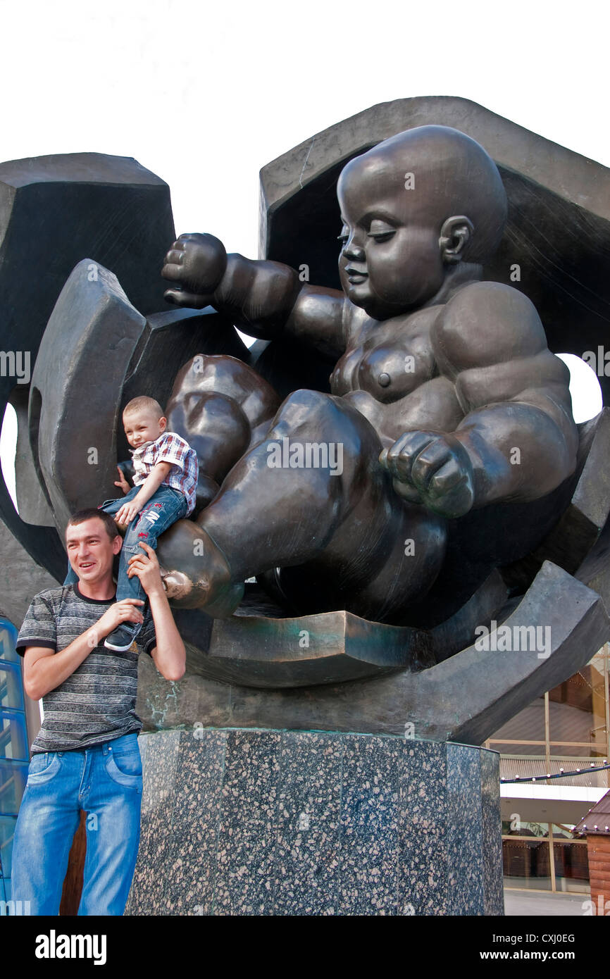 Vater und Sohn posiert mit Statue von Riesenbaby, das symbolisiert die Wiedergeburt der Stadt am Hafen von Odessa. Stockfoto