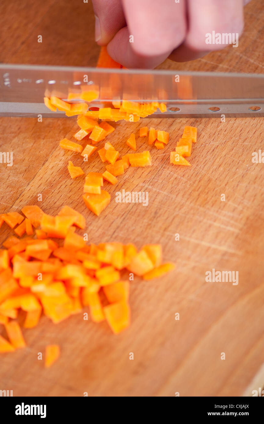 Nahaufnahme von Karotten wird von einem Koch auf einem Holzbrett gehackt Stockfoto