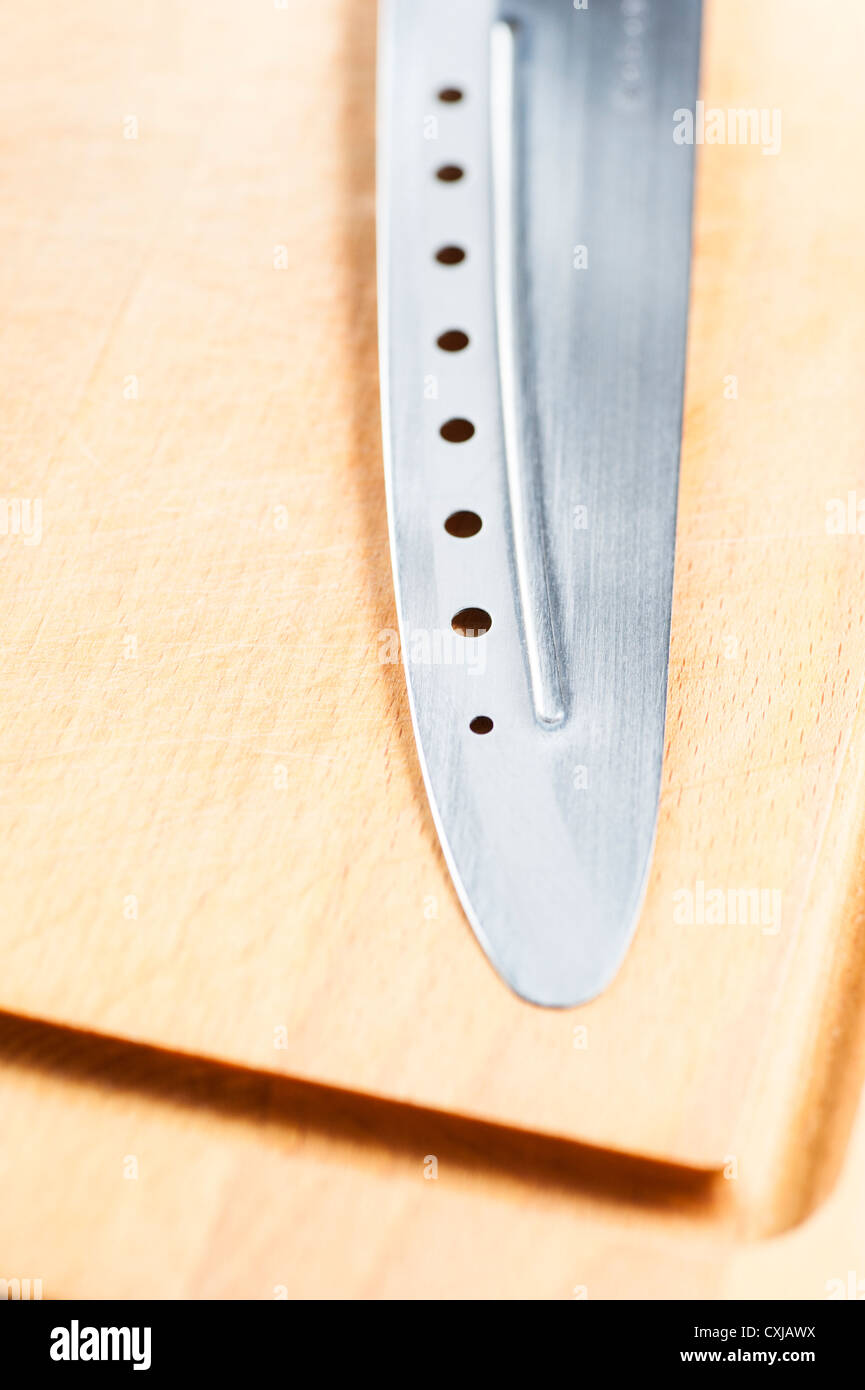 Messer mit Löchern auf Holzbrett liegend Stockfoto