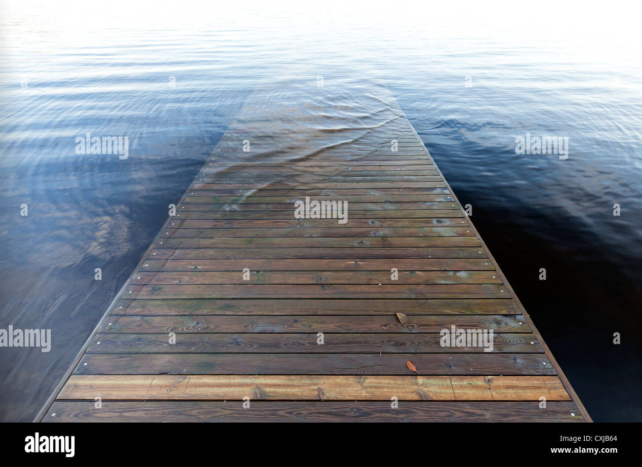 Perspektive von einem alten hölzernen Pier geht unter tiefblauem Wasser Stockfoto