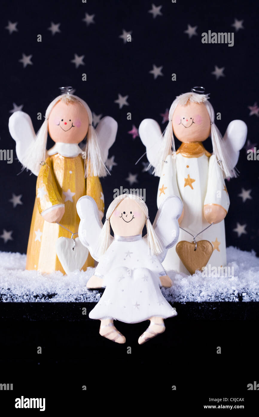 Drei goldenen und weißen dekorativen hölzernen Engel im Schnee vor einem Sternenhimmel schwarzen Hintergrund. Stockfoto