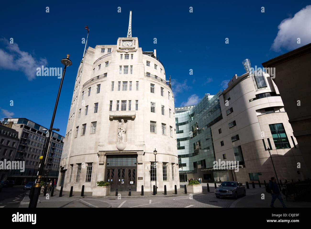 Ursprüngliches Art déco-Gebäude des BBC Broadcasting House in Portland Place mit der Erweiterung des neuen Sendezentrums rechts. London Großbritannien. Eine umstrittene Statue von Eric Gill wird gezeigt, bevor sie beschädigt wurde. Stockfoto