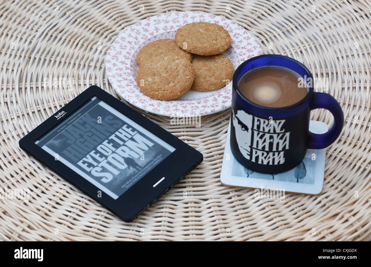 Eine Kobo Touch Ereader (Ebook) wird auf einem Tisch zusammen mit einer Tasse Kaffee und ein paar Kekse fotografiert. Stockfoto