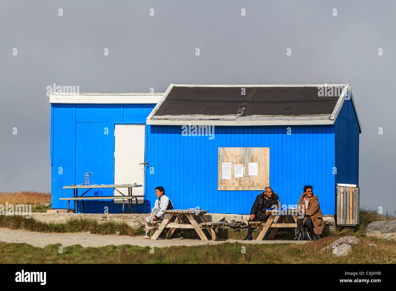 Zwei Frauen und ein Mann sitzen Ouside ein bunt bemalten Haus Itilleq, ein Dorf von 85 Inuit-Menschen in Grönland Stockfoto