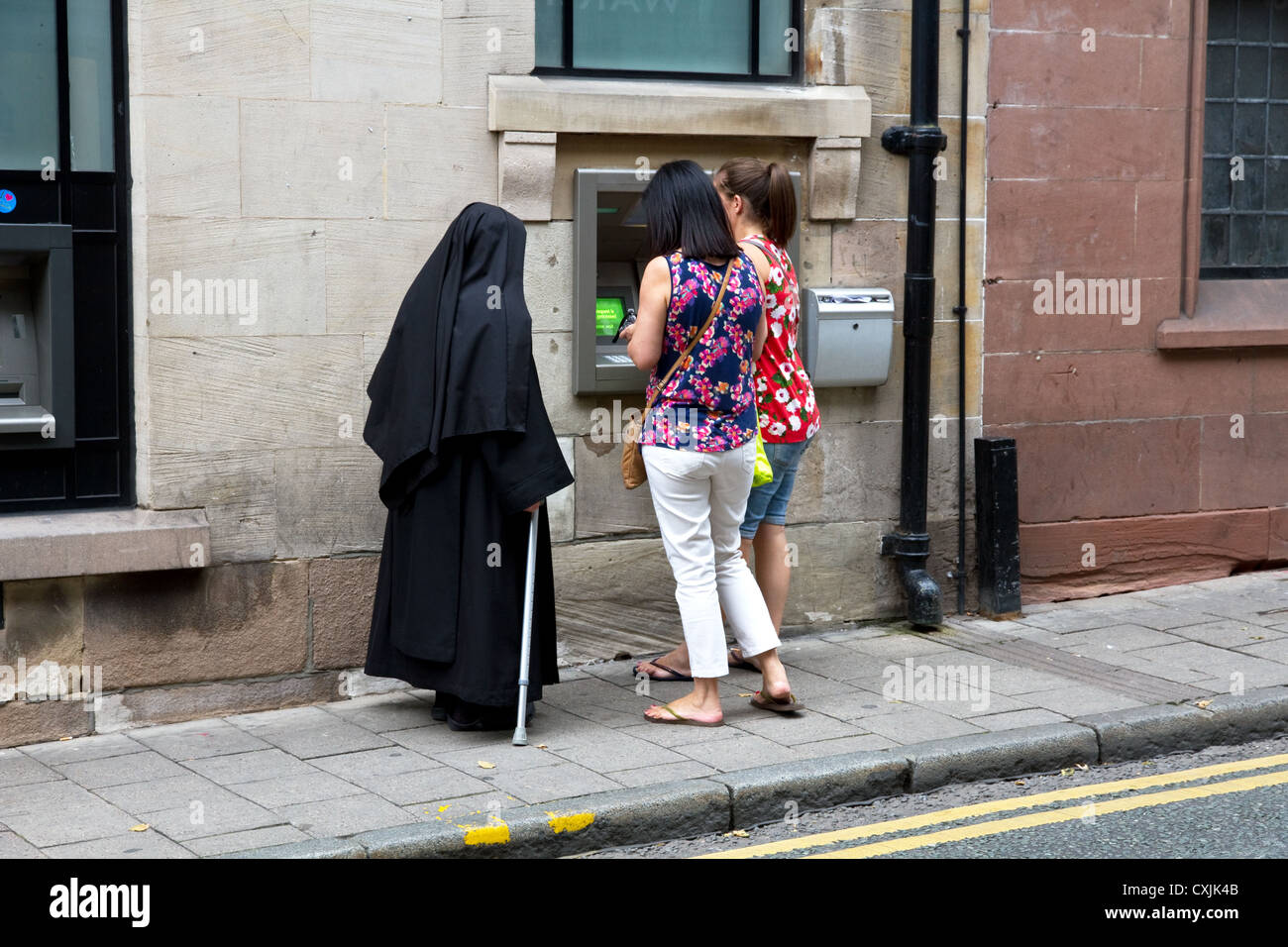 Nonne und zwei anderen Frauen am Geldautomat auf der Straße, Chester, Cheshire, England, UK Stockfoto