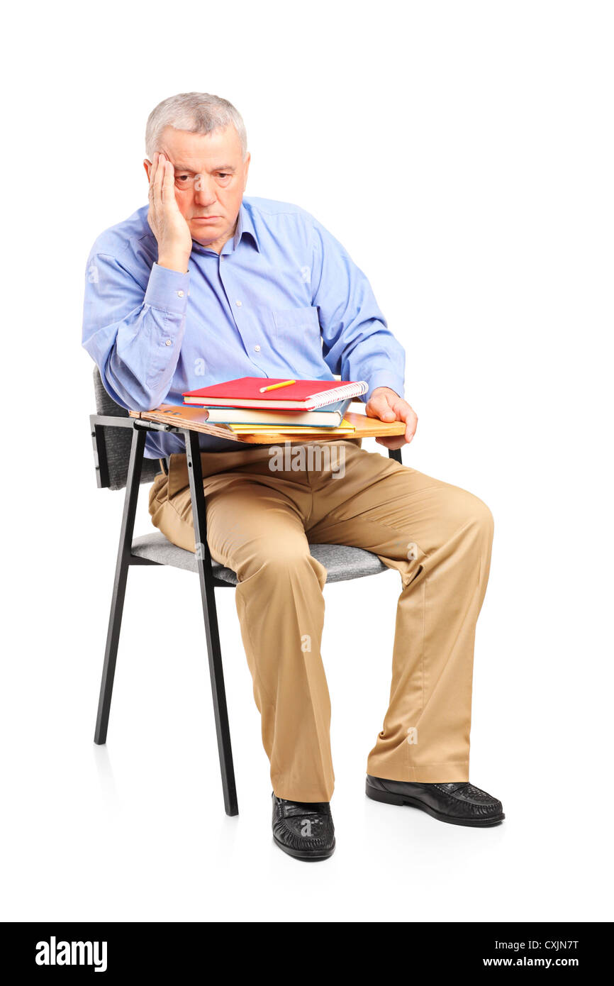 Nachdenklich reifer Mann sitzend auf einem Klassenzimmer Stuhl isoliert auf weißem Hintergrund Stockfoto