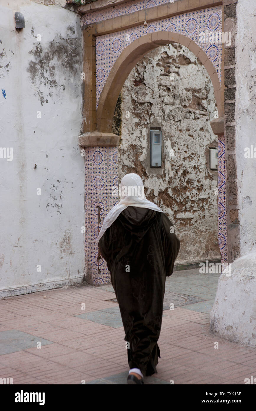 Lokalen Marokkanerin in Djellaba und Kopf Schal zu Fuß in Richtung eines Bogen Weg Essaouira, Marokko Stockfoto